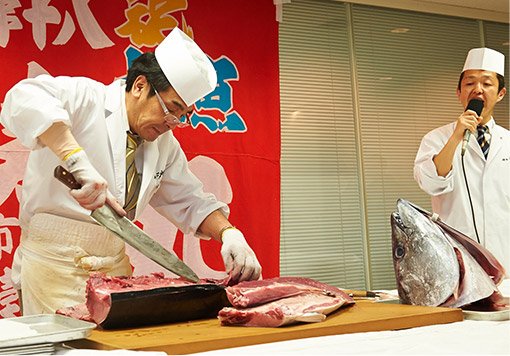 イベント広場のイメージです。寿司職人さんが大きな包丁を使って、国産本マグロをさばいている様子の写真です。