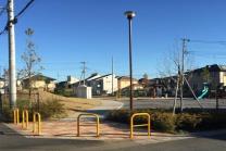 道路とつながる出入口に黄色いポールが設置されている公園の写真