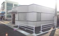 自由通路エレベーターが近くに見える道路の角にある白い壁の公衆トイレの写真
