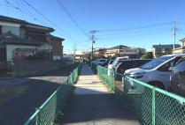 暗渠化された下水路の名残として両側に緑の金網が残っている歩道の写真