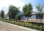 整備された植え込みと歩道の脇にある勤労者体育センターの写真