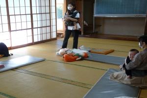 抱っこ紐で赤ちゃんを抱いて部屋の前に立つ講師の方の写真