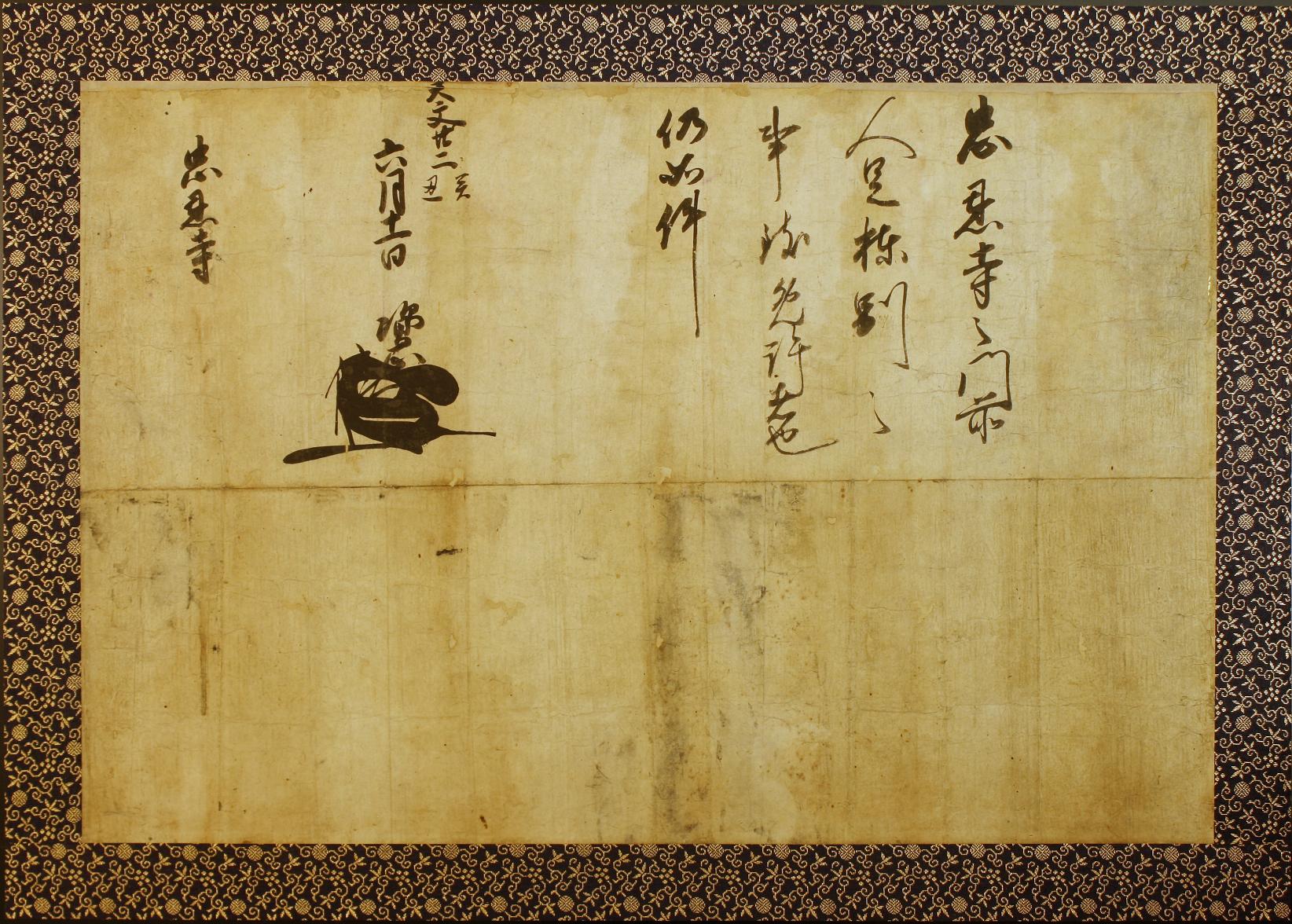 黒と金の和柄で縁取られ上半分の部分に文章が書かれている太田資正棟札免許状の写真