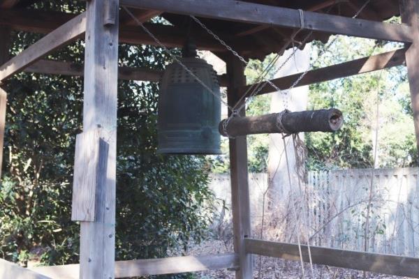 木造の鐘楼の中に吊り下げられた撞木と梵鐘の写真