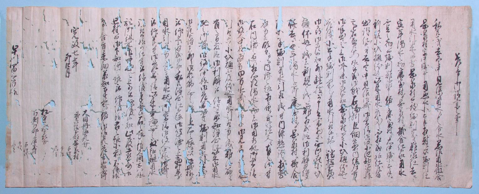 横長で所々破れたり穴が開いている紙にびっしり文字が書かれている新井筋堀割出入内済請書の写真