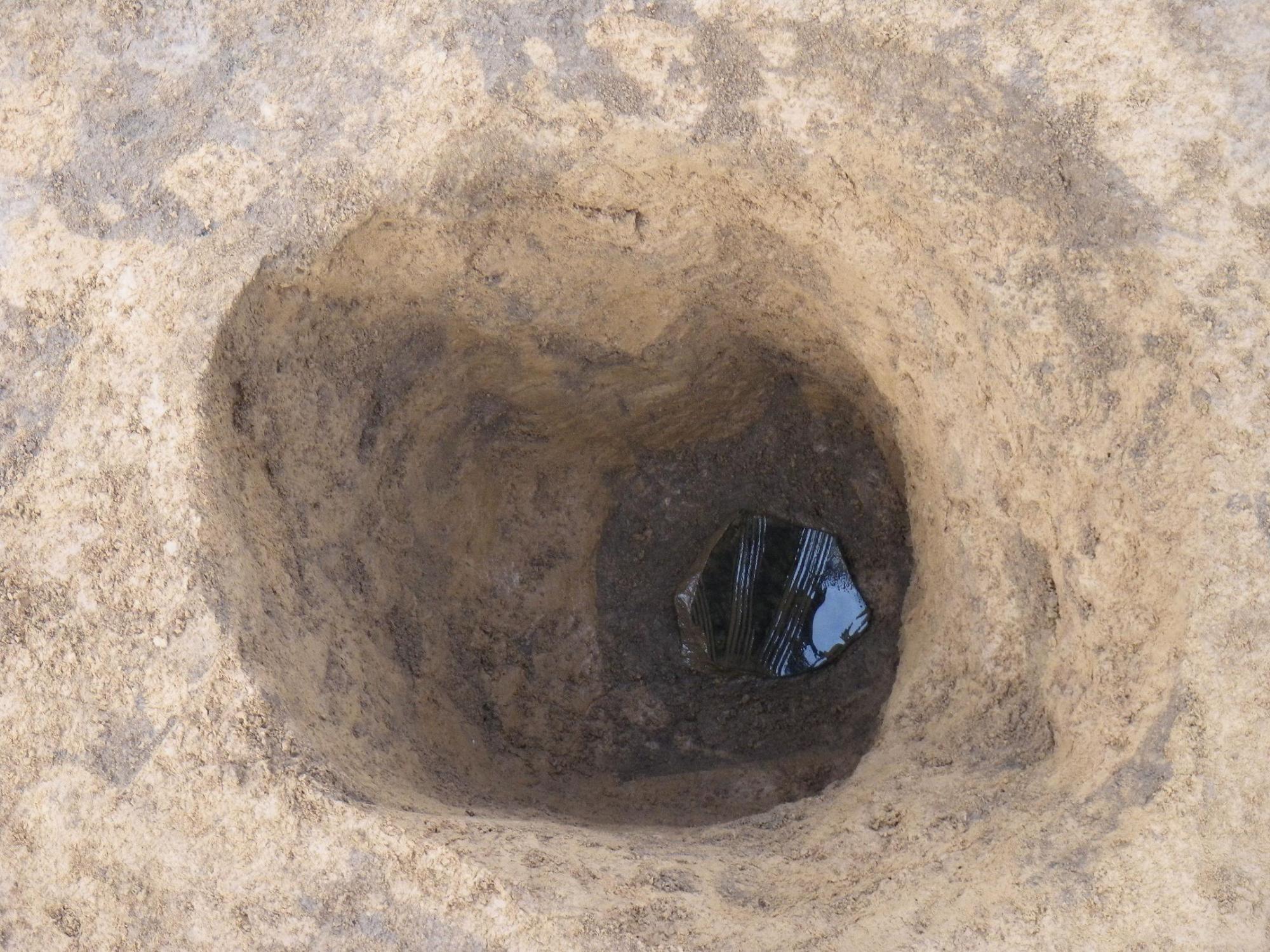 柱穴の底に出土した陶磁器片をアップで撮影した写真
