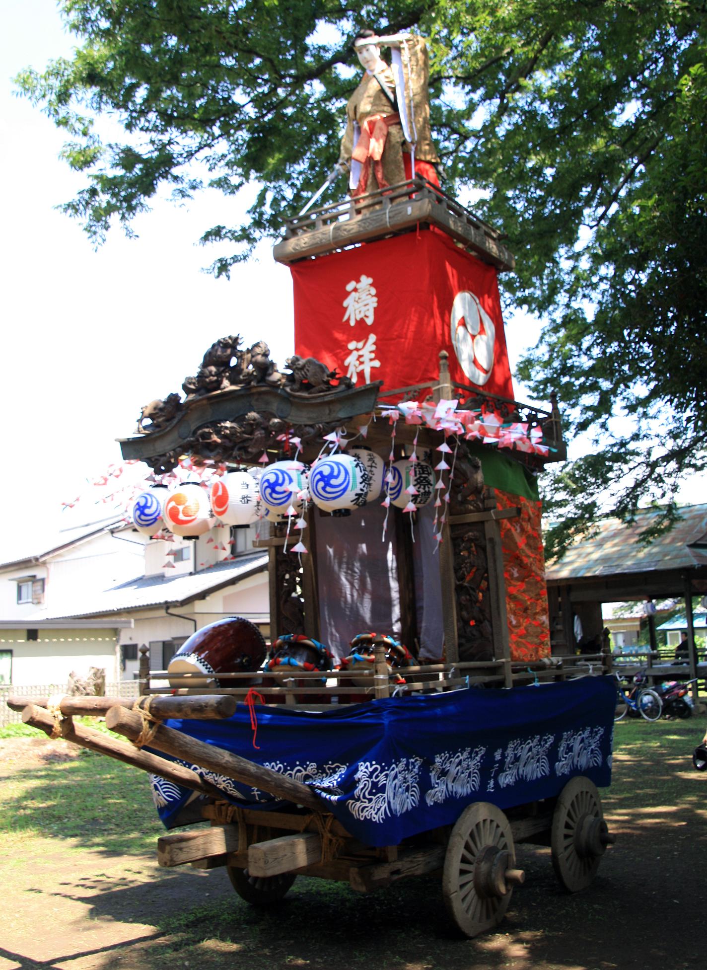 唐破風屋根の上下に鬼板と龍の懸魚が飾り付けられ沢山の提灯を吊り下げた山車の写真