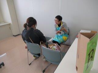 お母さんに抱っこされている赤ちゃんに笑顔で話をするエプロンを付けた職員の方の写真
