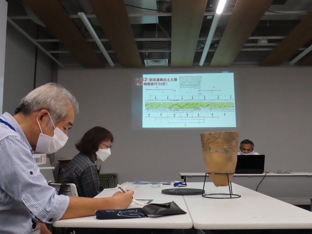 プロジェクターで写し出された資料を見ながら説明を受ける参加者の方々の様子を横から撮影した写真