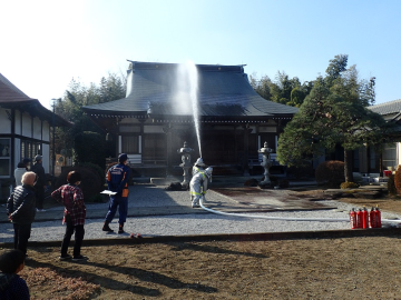 消防士の方が2名でポンプ車のホースから青雲寺の屋根に向かって放水を行っている様子の写真