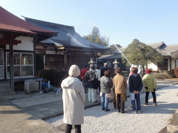 青雲寺へのポンプ車での放水の様子を少し離れて見ている地域住民の方々の写真