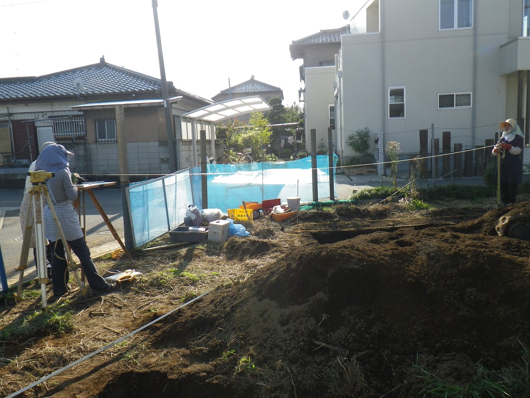 道路と区画の境目から発掘した右側まで真っ直ぐ紐を張っている作業員の写真