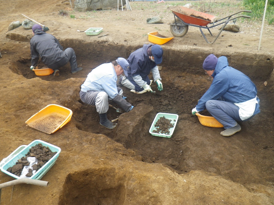 4名の調査員の方が遺跡の中に入り、土を丁寧に堀り起こし発掘作業をしている様子の写真