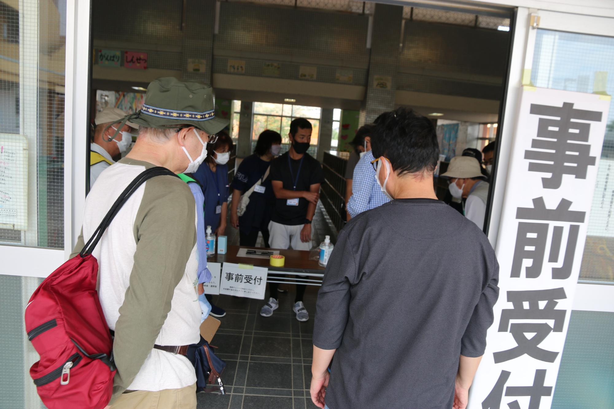 体育館入り口に設置された事前受付所に訓練に参加された方が受付をしている写真