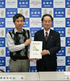 ベストを着た男性とスーツを着た男性が一緒に提言書を持っている写真