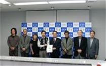 関係者の男女8名が横一列に並び記念撮影をしている写真