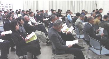 多くの参加者が席に着き、資料を手に持って話を聞いている白岡町自治基本条例素案発表フォーラムの様子の写真