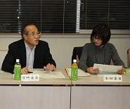 2名の参加者が席に座っており、左側の男性が話をしている様子を右側の女性が手元の資料を持ちながら見ている写真