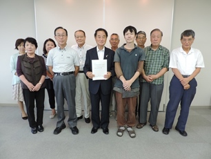 会議に参加された男女が2列に並び、前列中央の男性が答申書を持っている写真