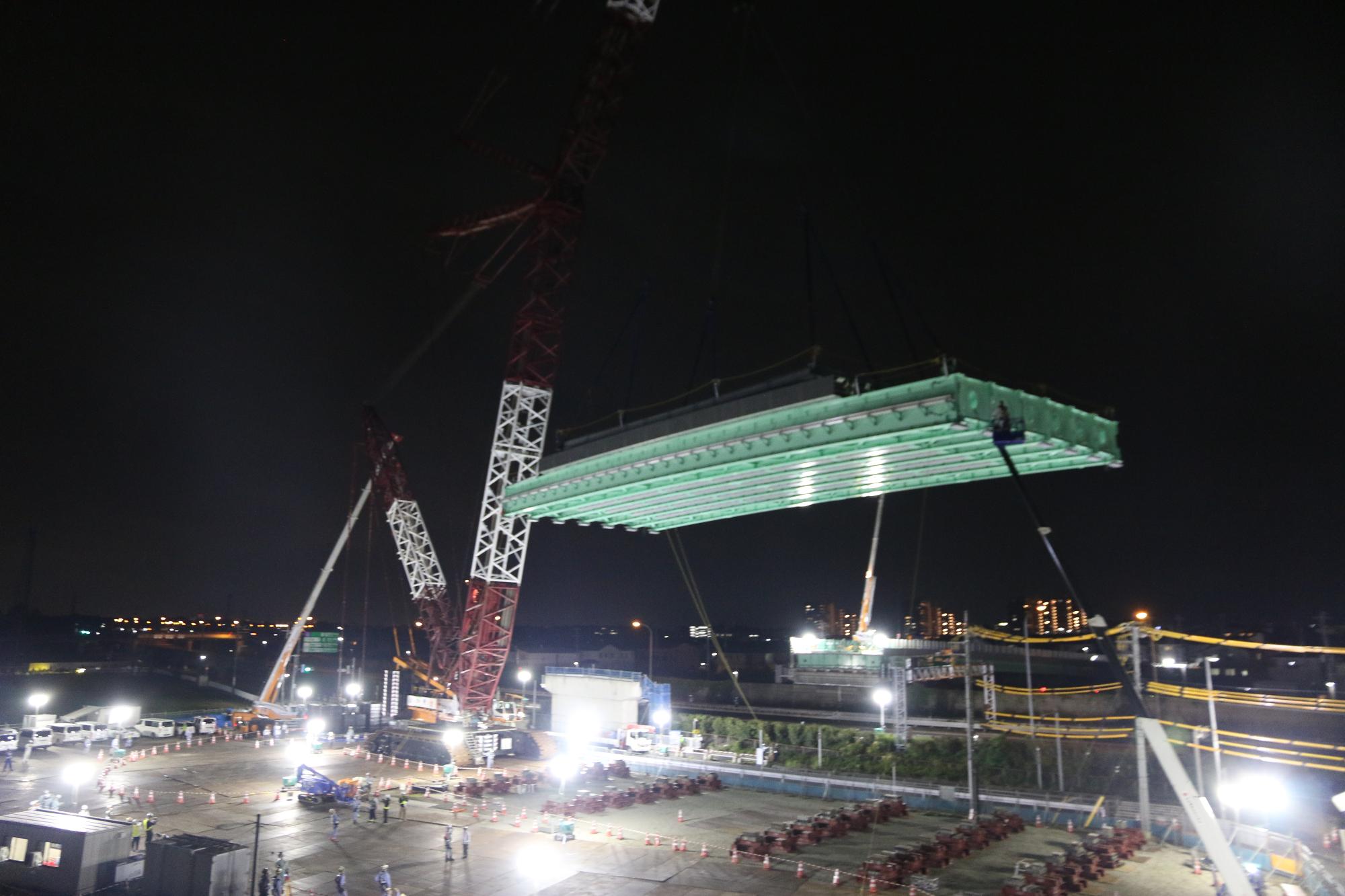 大型クレーンが橋桁を吊っている写真