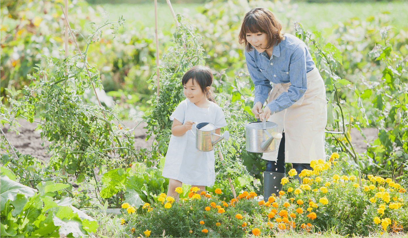 女性と女の子が笑顔で花に水をあげている様子