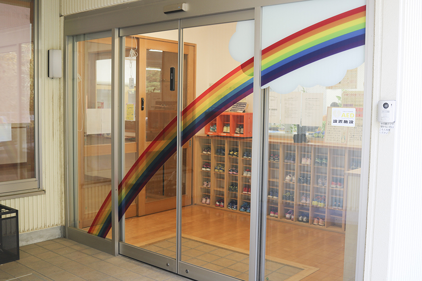 ガラスのドア一杯に虹の帯が描かれているエントランスの写真