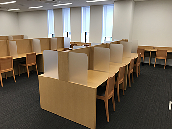 パーテーションで区切られた4人掛けの机が並ぶ学習室の写真