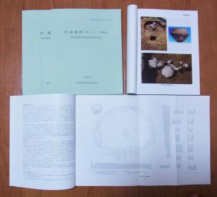 報告書の開いて写真が掲載されたページ、A3サイズに図が記載されたページ、2冊を並べて置かれている発掘調査報告書の写真
