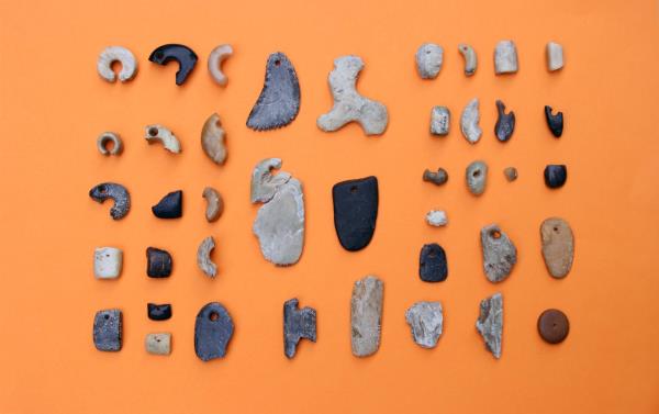 タタラ山遺跡で出土された様々な大きさの勾玉や石器が展示されている写真