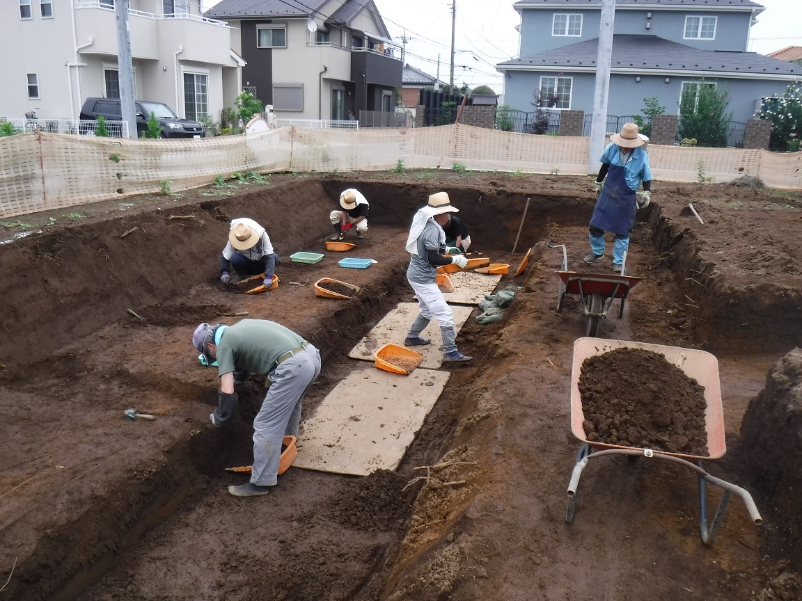 調査区内の地面を掘り確認する作業を行っている6人の作業者の方々の写真