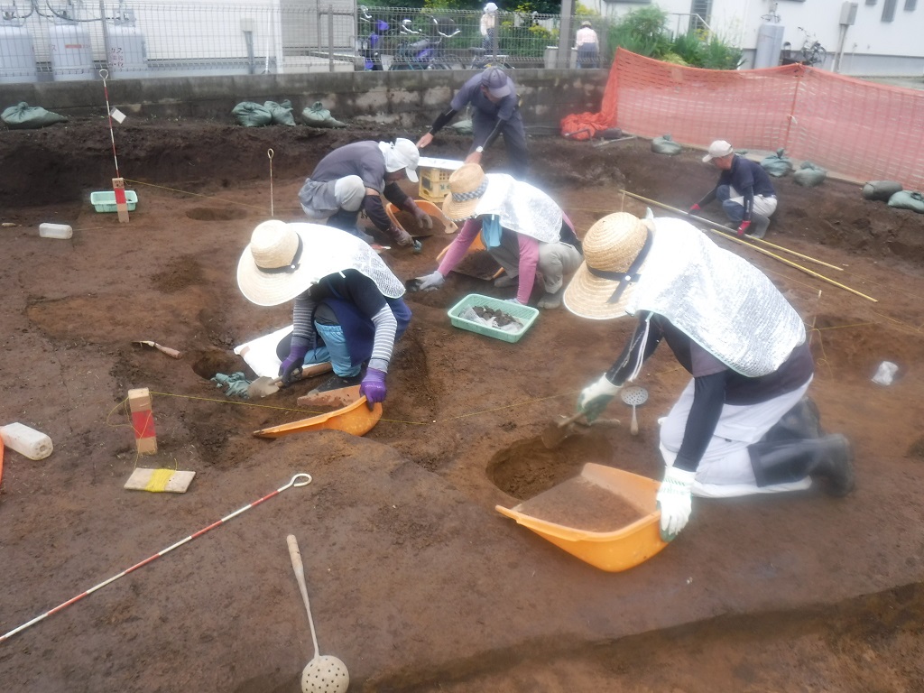 調査区域内の地面をスコップで掘り、出土品を探している調査員の写真