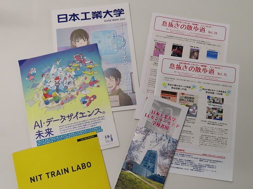 日本工業大学のパンフレットやニュースレターなどが机の上に広げて置かれている写真