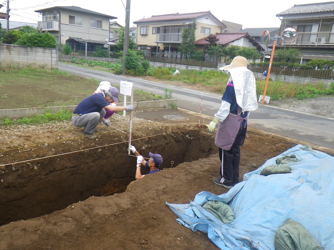 深く彫った土の中に入り発掘調査を行っている調査員の方々の写真