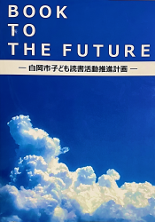 大きな入道雲がかかる青空の写真に「BOOK TO THE FUTURE」と書かれた白岡市子ども読書活動推進計画の表紙の写真