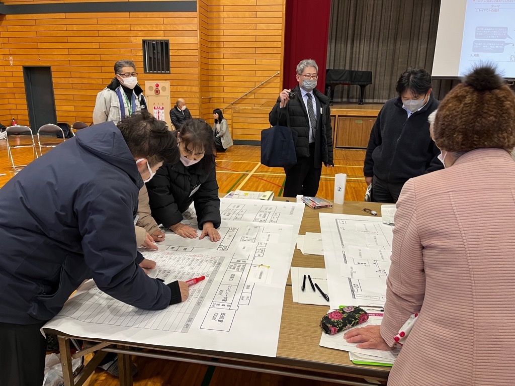 部屋の前方に一列に並び職員の方の説明を聞く参加者の人達を後ろから撮影した写真