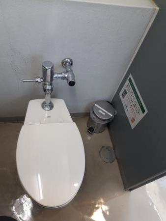 洋式トイレと、その斜め横の隅に置いてある、サニタリーボックスの写真