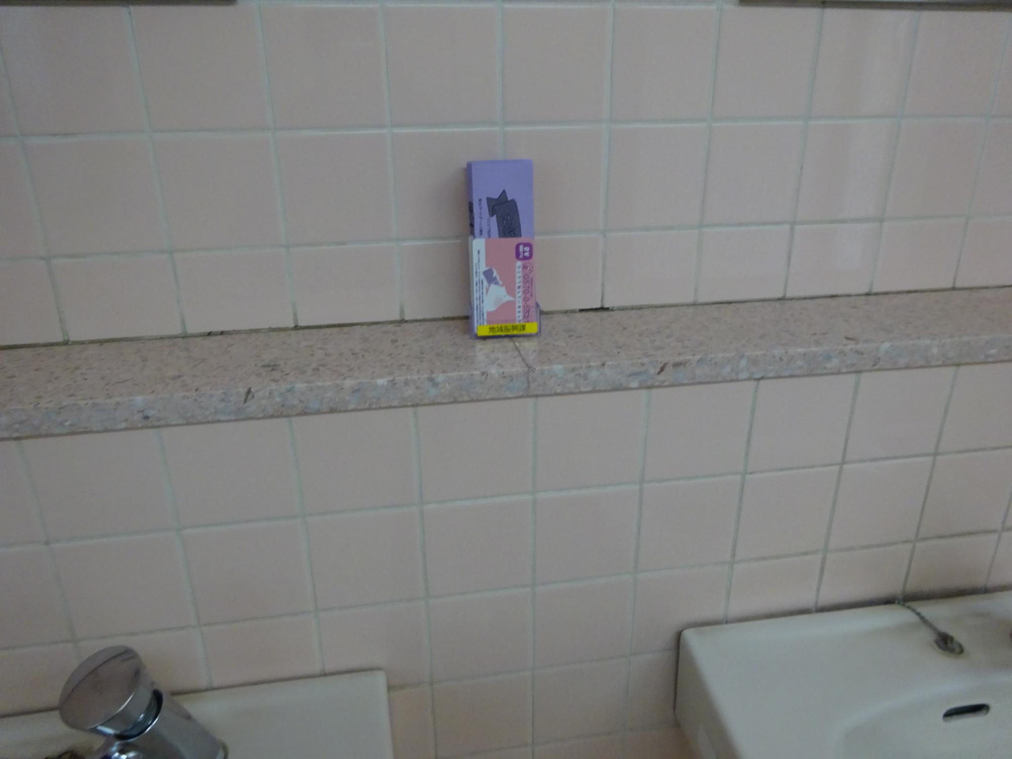 2つのシンクがある手洗い場の棚にDV相談ナビ啓発カードが置かれている写真