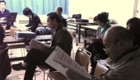 参加者の方々が席に着き、真剣な表情で資料に目を通している地域説明会の様子の写真